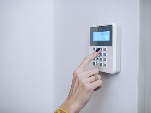 A hand typing in an alarm code for a house alarm system
